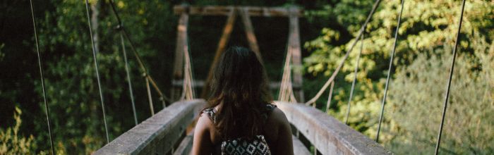 Femme de dos sur un pont en bois.